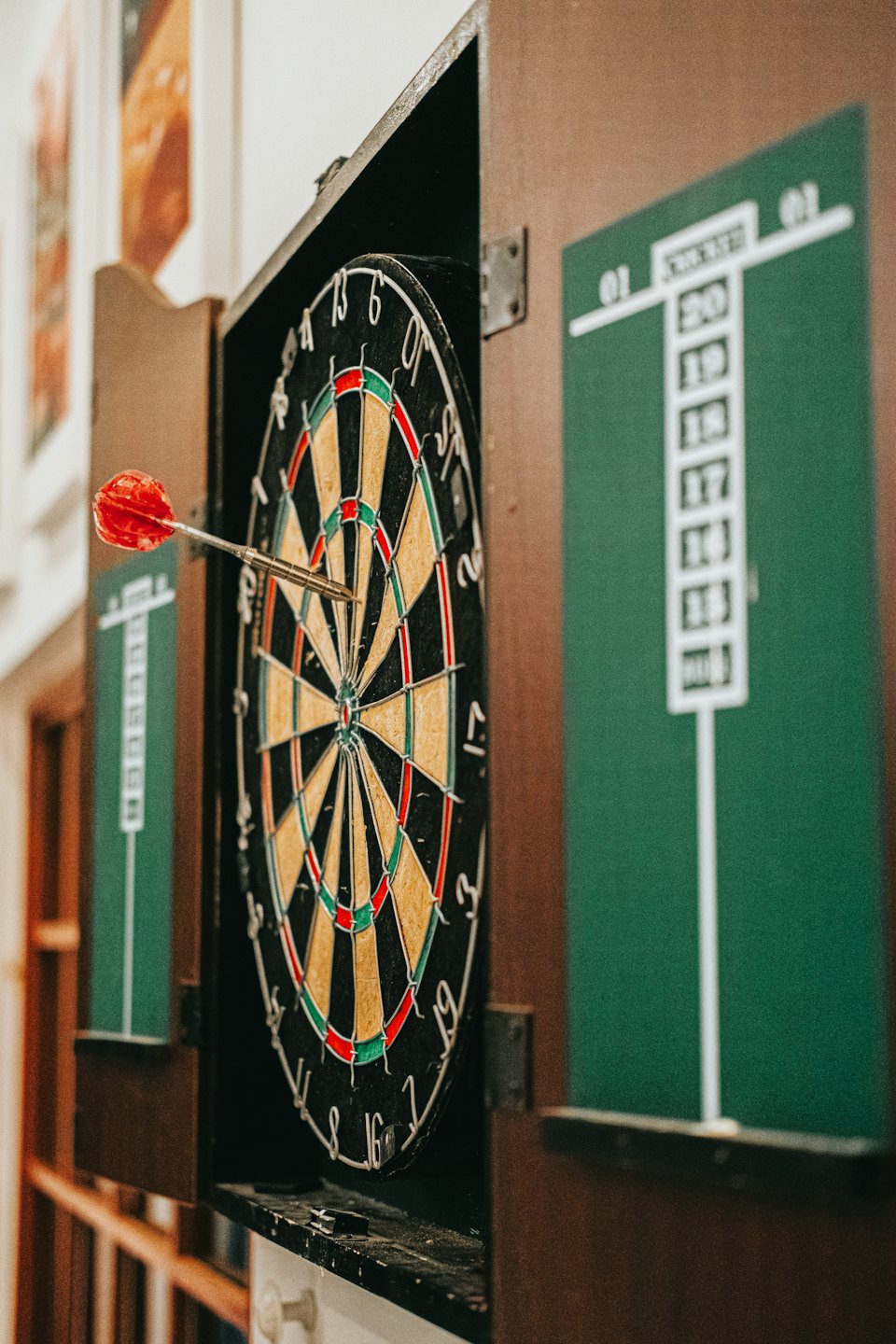Holz-Dartscheibenschrank mit einem Dart in der Scheibe.